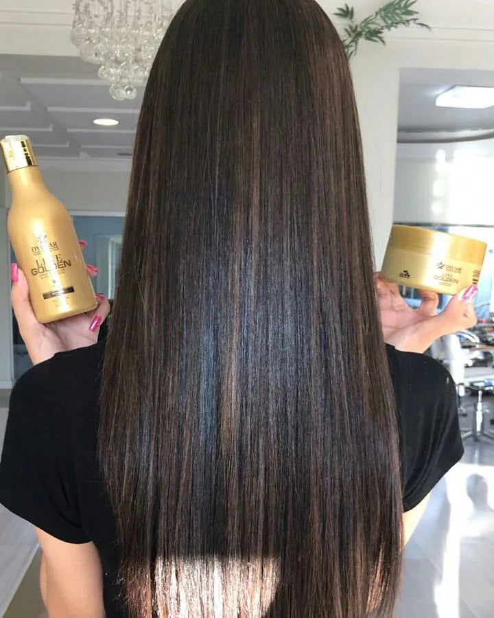 Mulher vista de costas exibindo seu cabelo longo, liso e com brilho espelhado, enquanto segura o shampoo e a Máscara de Hidratação Dyusar Line Golden.