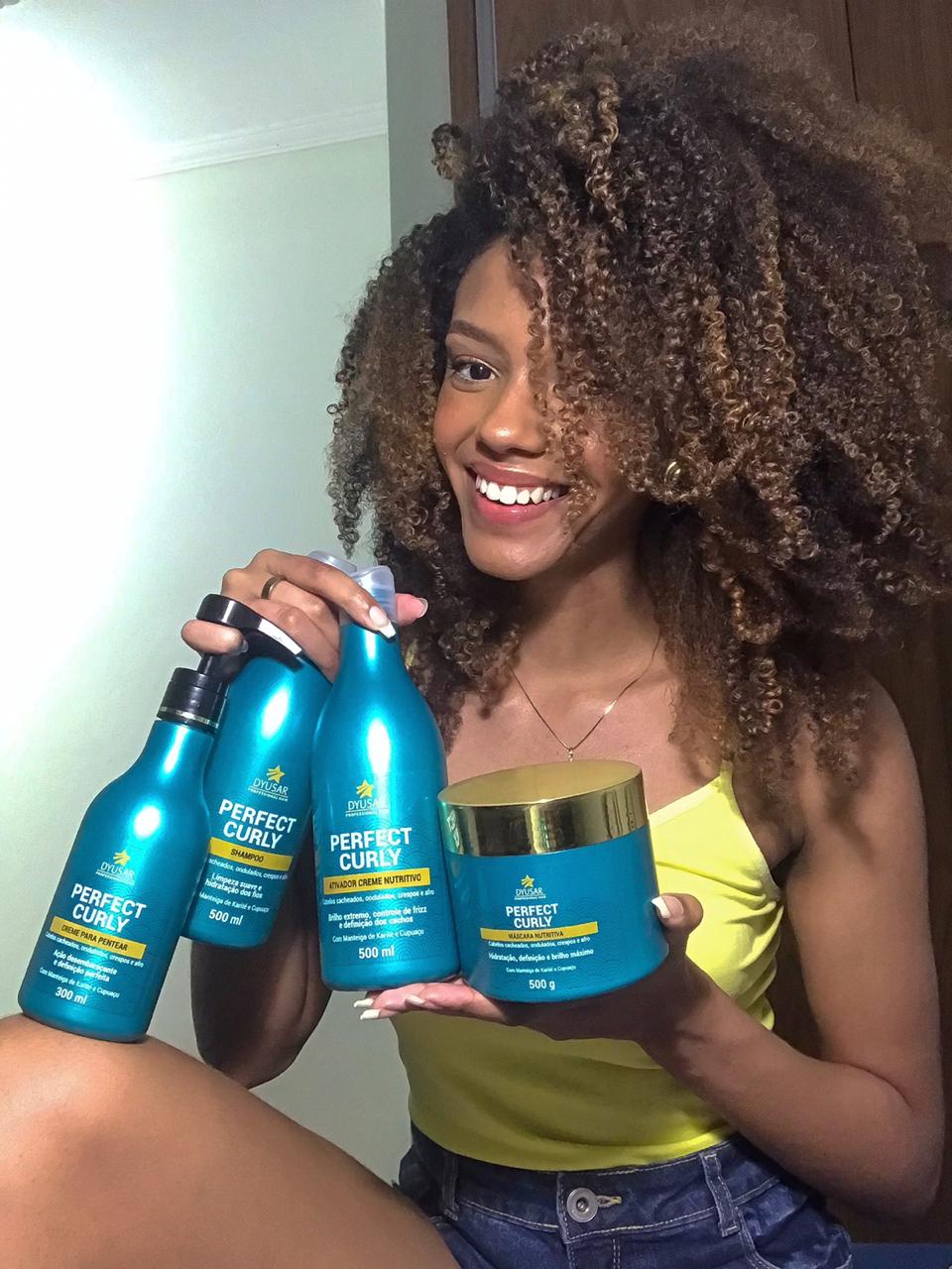 Modelo sorrindo com cabelo crespo e volumoso, mostrando a linha completa de produtos Perfect Curly, que inclui o Shampoo para Cabelos Cacheados.