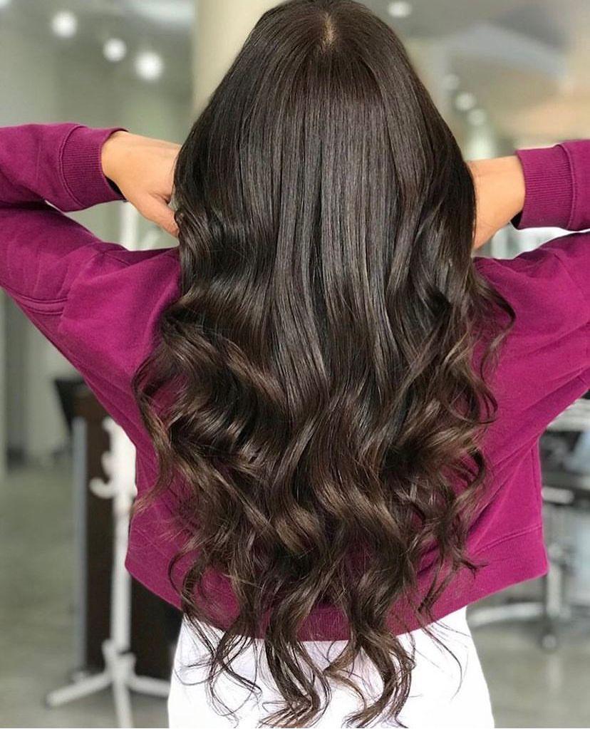 Mulher de costas com cabelo longo, castanho escuro e ondulado, mostrando a cor vibrante e o aspecto saudável após o uso da Coloração Permanente Dyusar Color Live 6.7