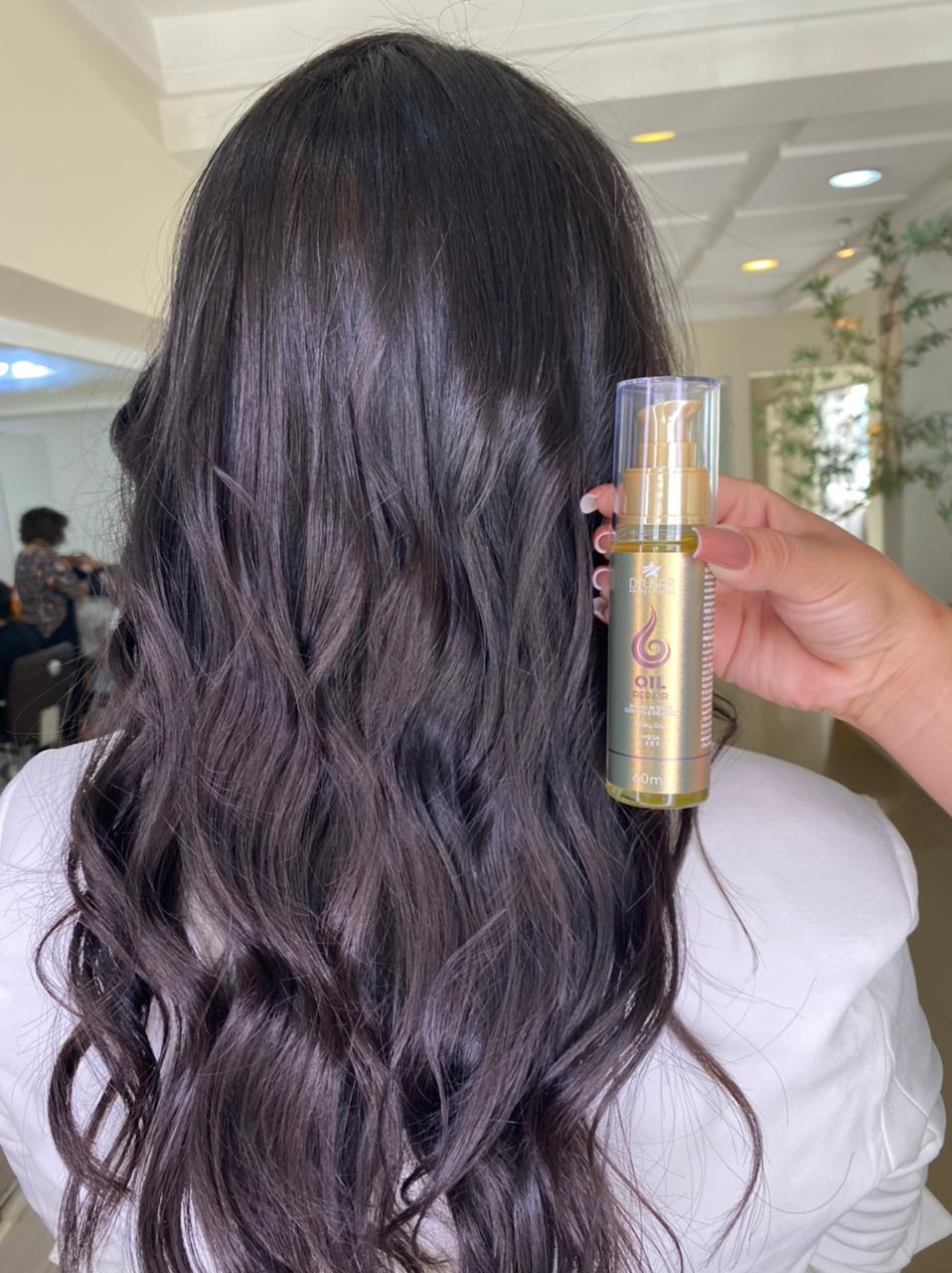 Cabelo longo, escuro e ondulado de uma cliente, com o frasco do Óleo Reparador de Pontas Line Golden ao lado para mostrar o resultado de brilho e definição.