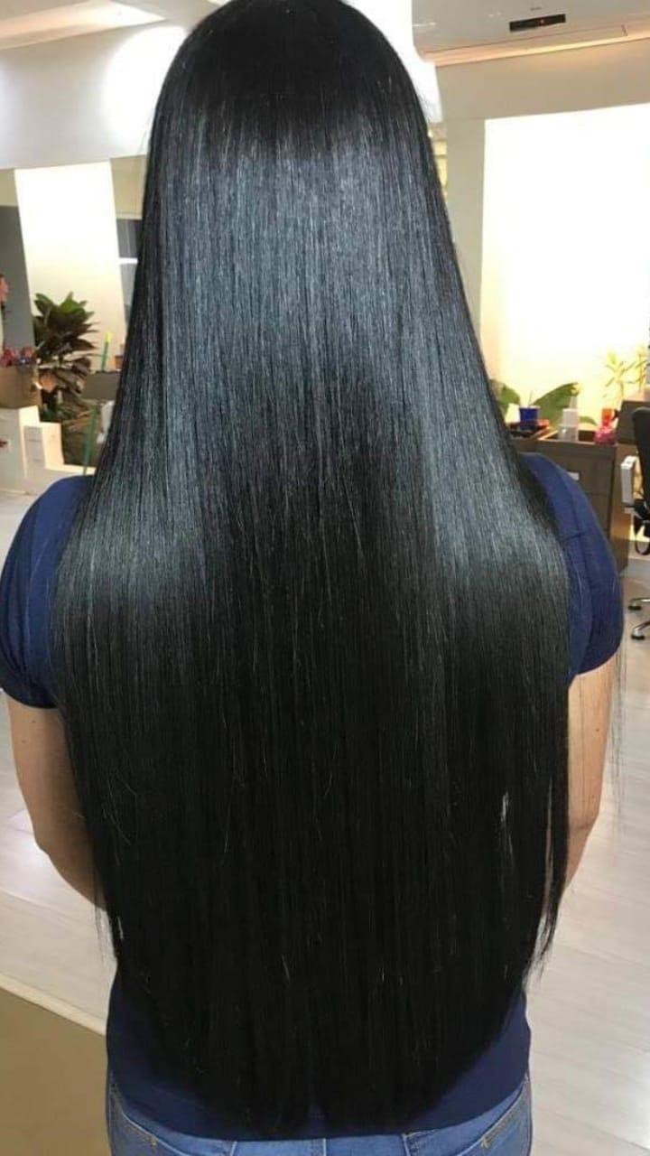 Mulher de costas com cabelo preto, longo e extremamente saudável, mostrando o resultado de fios fortes e resistentes, obtido com o tratamento do Tônico Anti Queda.