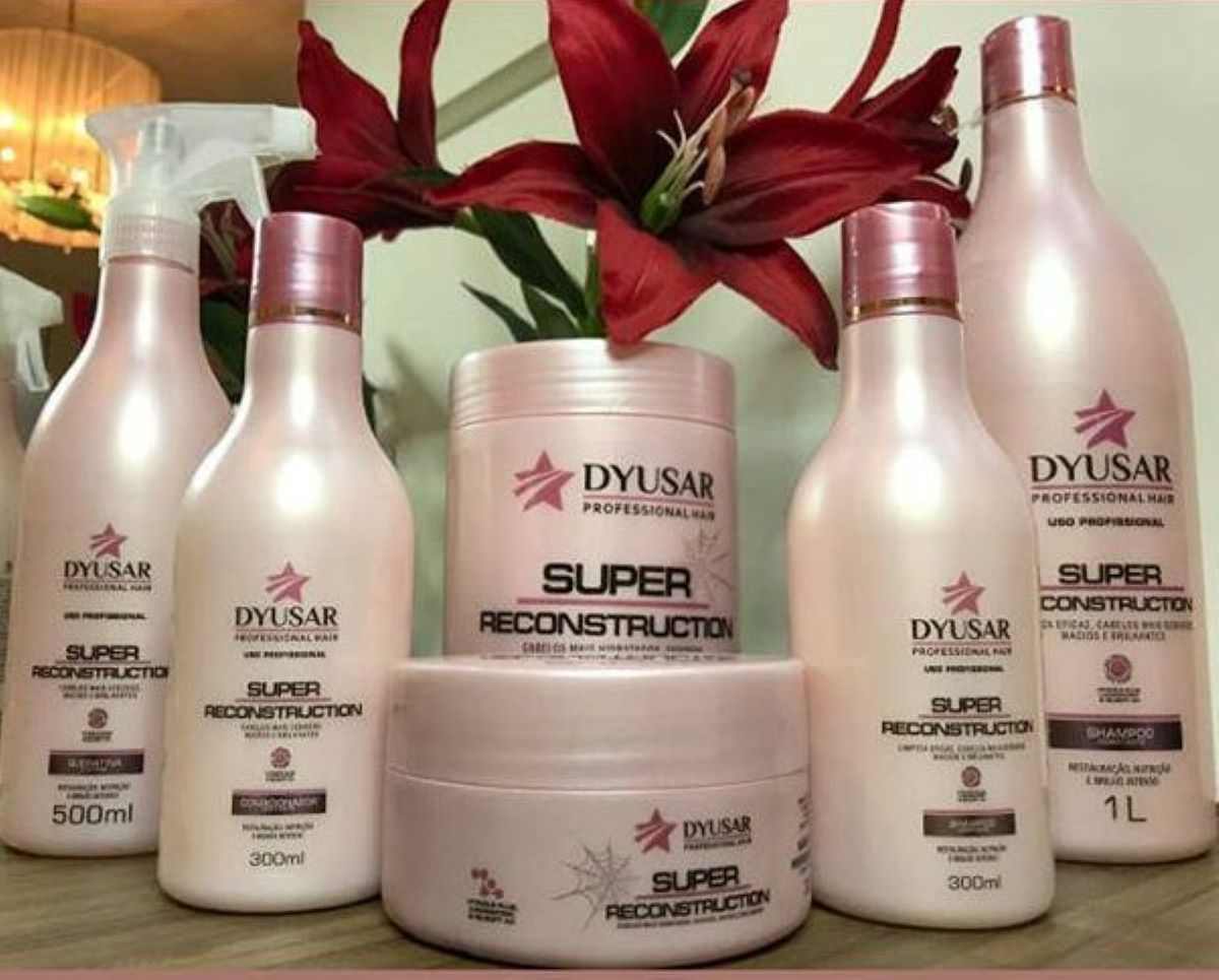 Toda a linha Super Reconstruction da Dyusar, que forma o Kit de Reconstrução Capilar profissional, em exibição com flores.