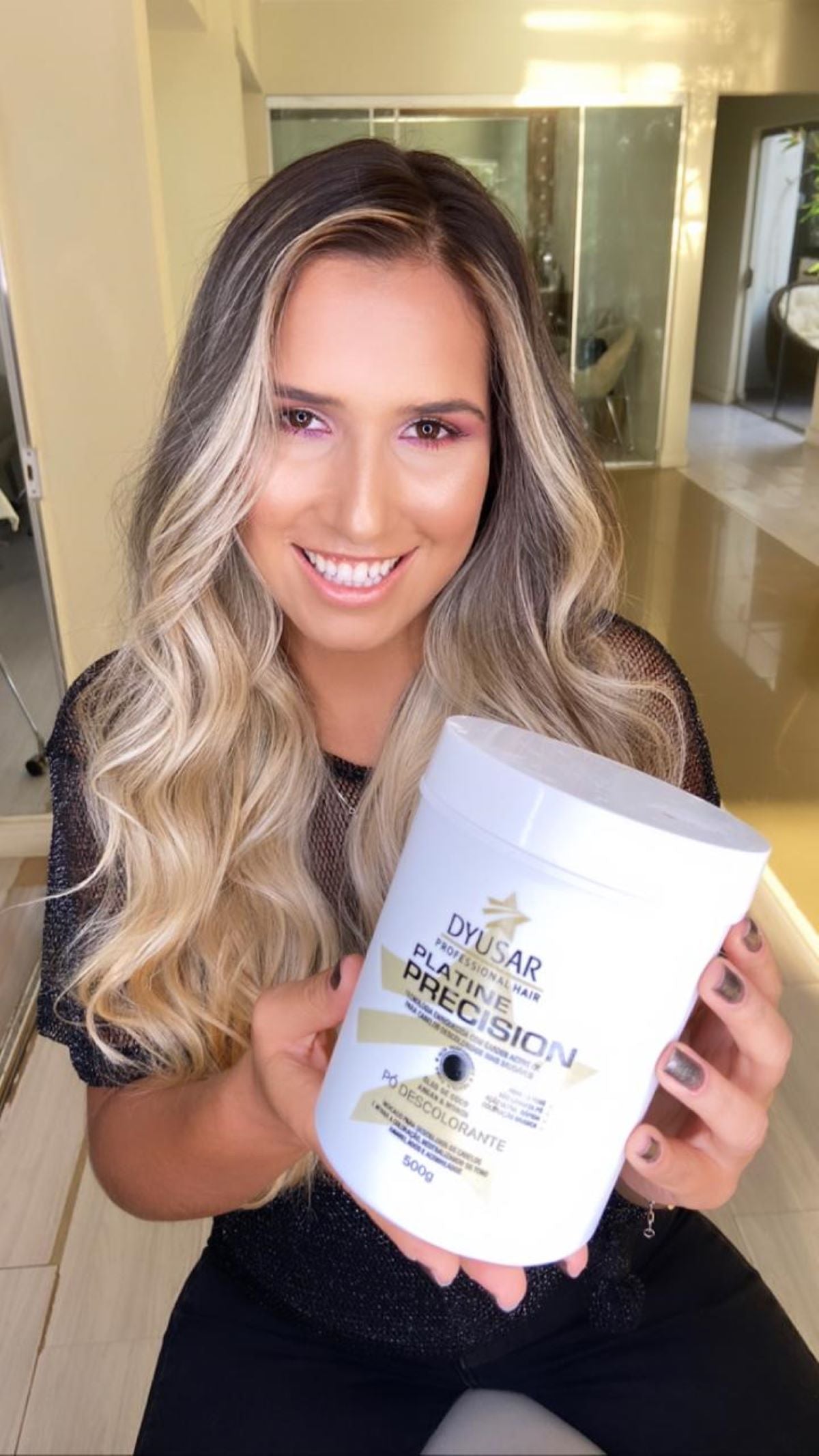 Modelo loira sorrindo e segurando o pote de 500g do Pó Descolorante Azul Platine Precision.
