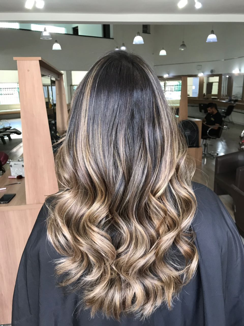 Cabelo com luzes e ondas de uma cliente vista de costas em um salão, mostrando o resultado final vibrante após a preparação dos fios com o Shampoo Detox.