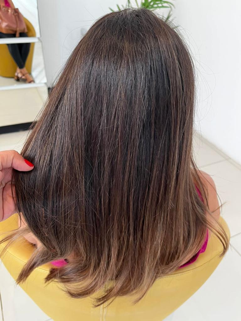 Mulher de costas com cabelo longo, castanho escuro e ondulado, mostrando a cor vibrante e o aspecto saudável após o uso da Coloração Permanente Dyusar Color Live.