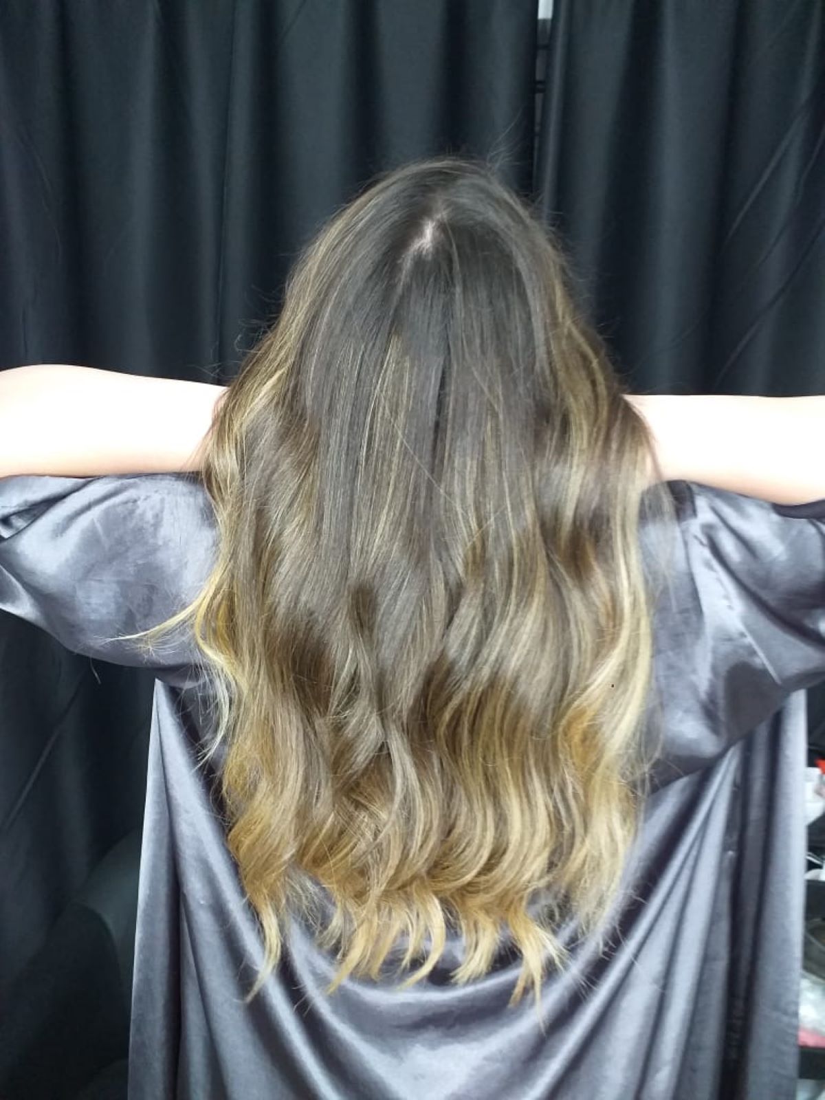 Cabelo longo e ondulado com luzes de uma cliente em um salão, mostrando o resultado saudável e a cor vibrante obtida após a preparação dos fios com o Shampoo Desintoxicante Detox.