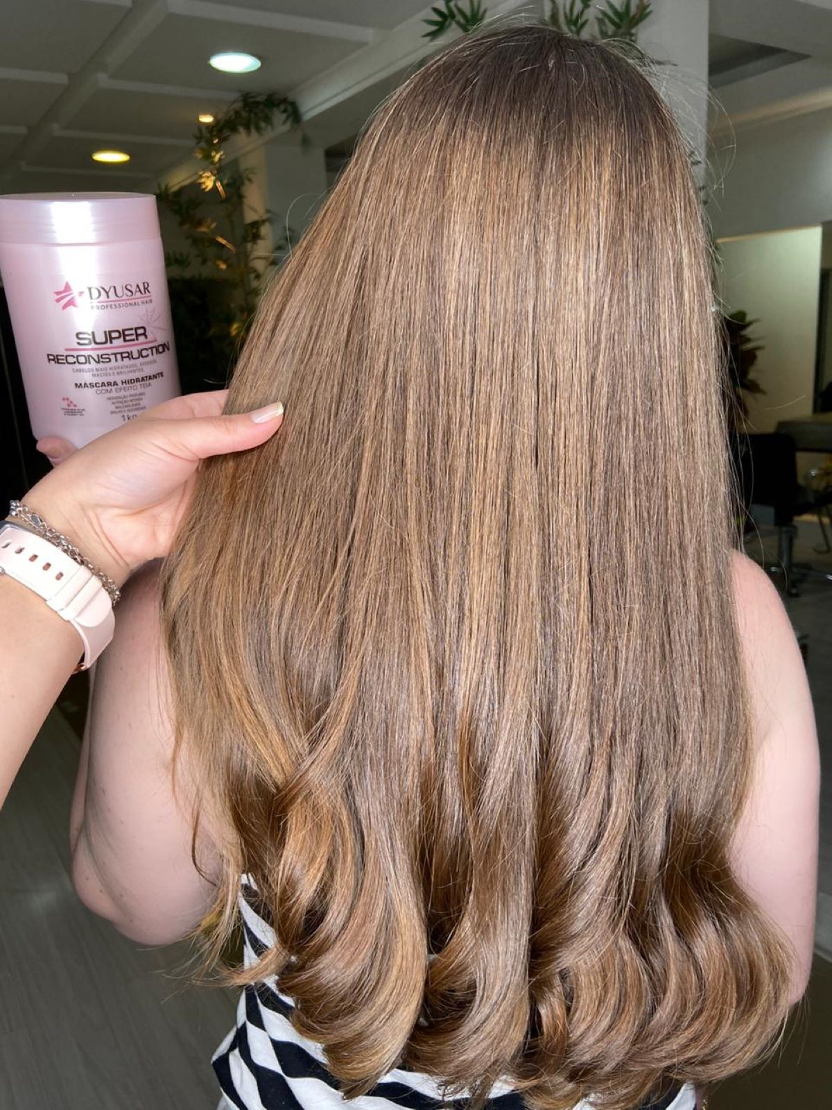 Mulher de costas com cabelo loiro e ondulado, mostrando o resultado da Máscara de Reconstrução Super Reconstruction, parte do kit.