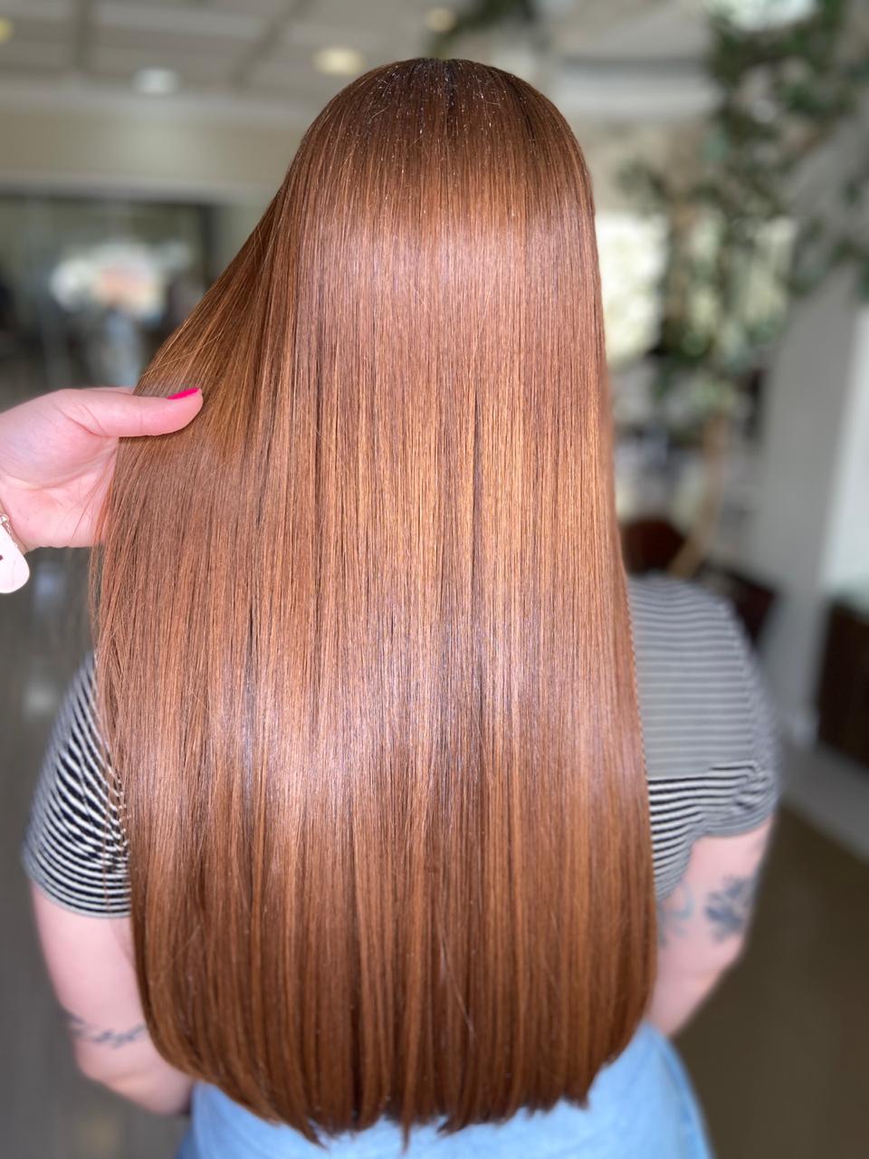 Mulher de costas com cabelo ruivo, longo e liso, mostrando o resultado de brilho e saúde após o uso do Leave-In Reconstrutor Super Reconstruction de 500ml