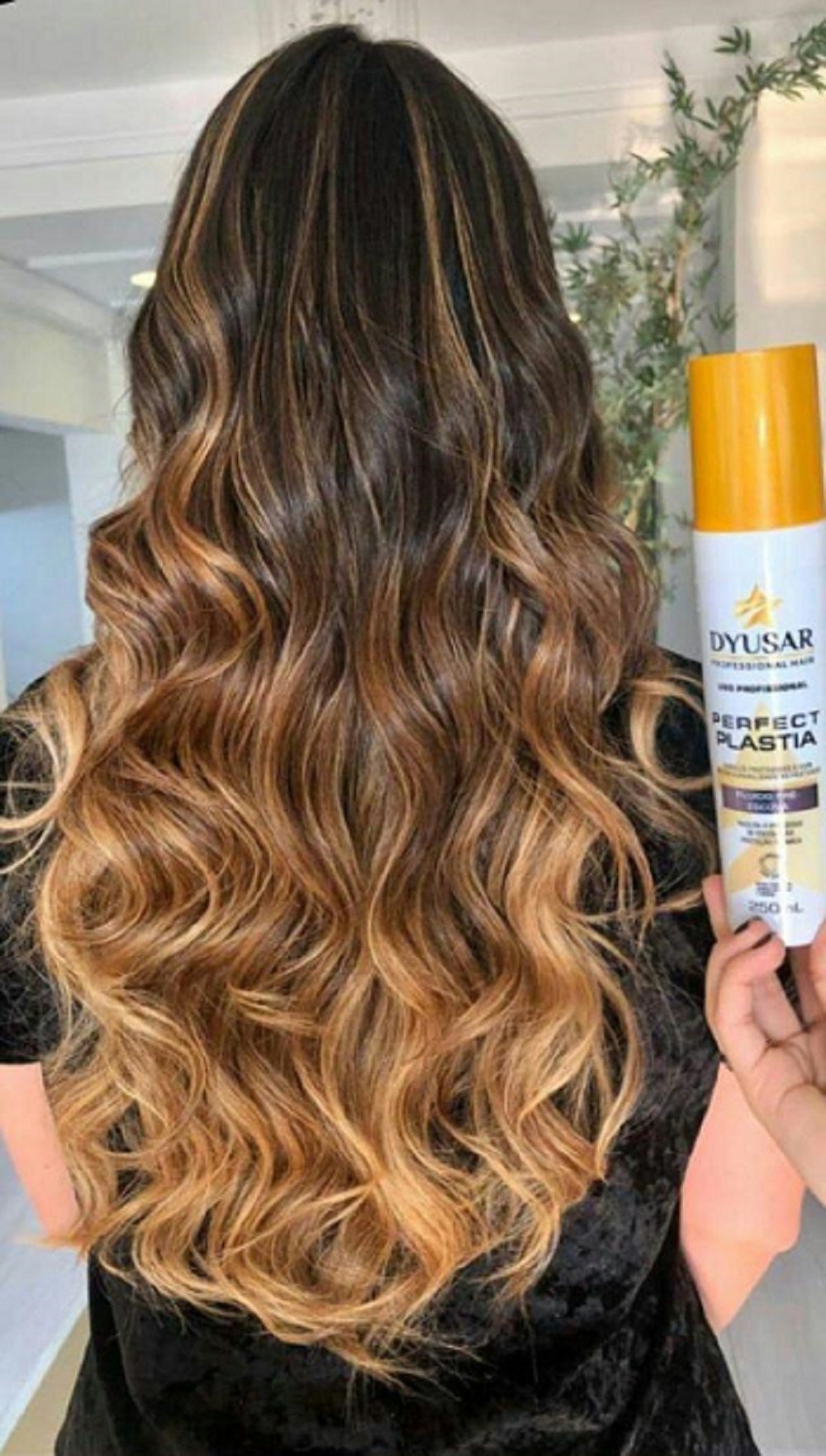 Cabelo longo com luzes ombré e ondas definidas, mostrando o resultado de brilho e proteção do penteado ao lado do frasco do Protetor Térmico e Fluido Pré-Escova Dyusar.