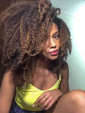 Close-up de uma mulher com cabelo crespo volumoso e com luzes, mostrando a definição e o volume obtidos com o tratamento da linha Perfect Curly, que inclui o Shampoo para Cabelos Cacheados.