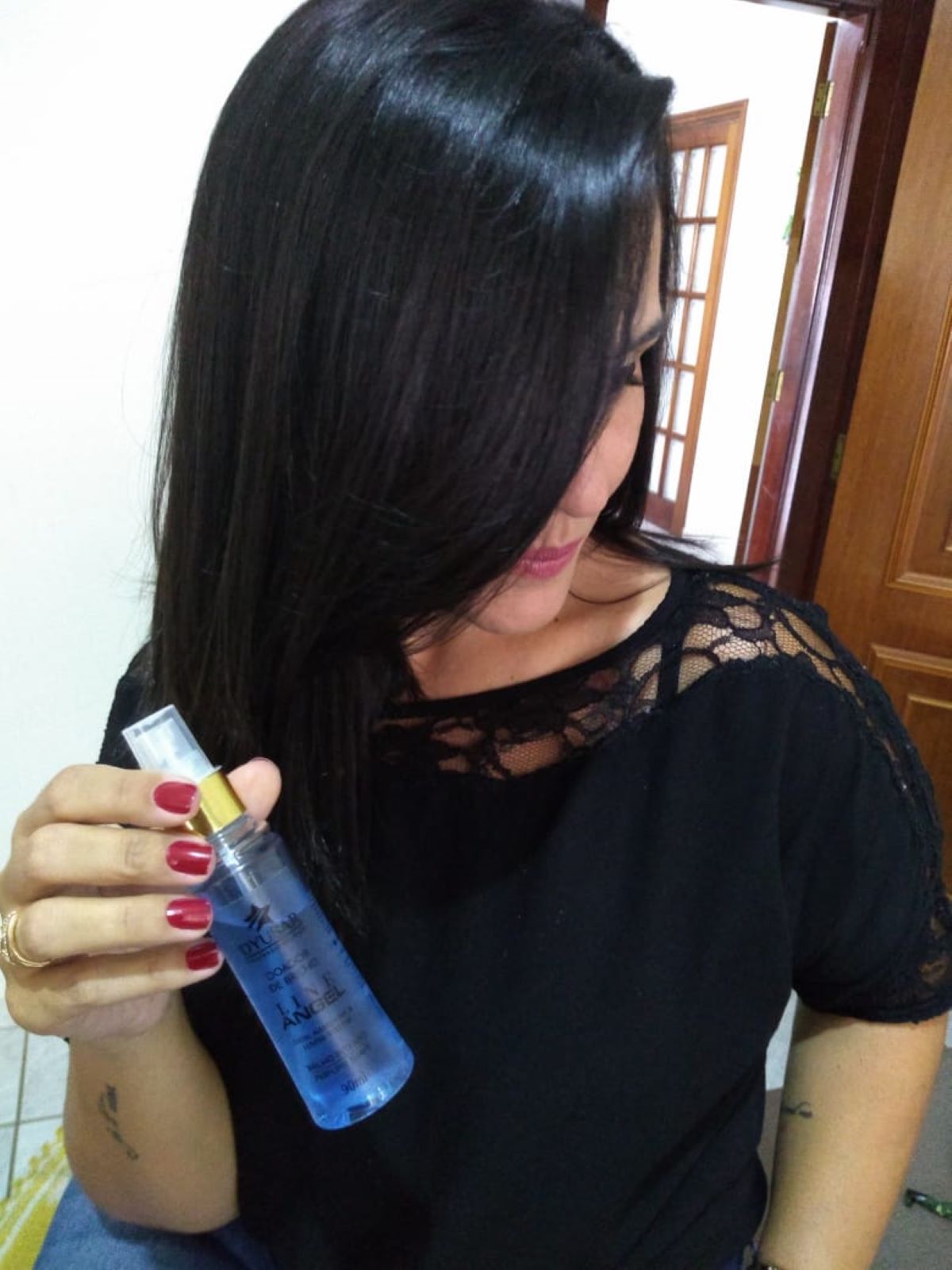 Mulher com cabelo preto, liso e brilhante, segurando o frasco do Spray de Brilho e Perfume Capilar Line Angel.